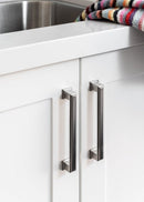 Close-up of white kitchen cabinets with metallic handles and a colorful towel on a shelf.
