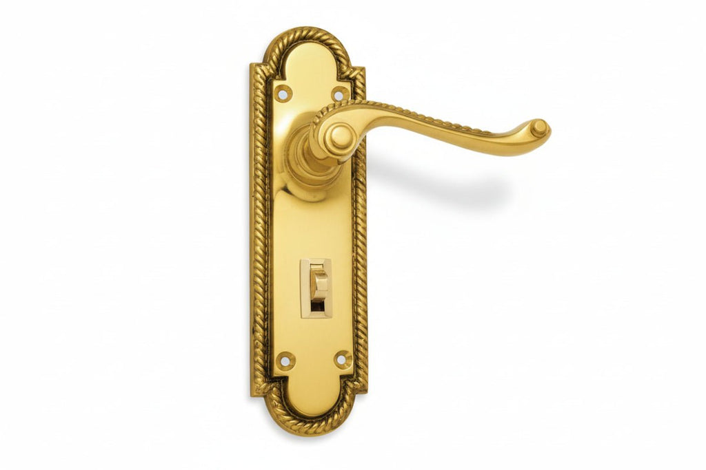Gold door handle with decorative frame on a white background