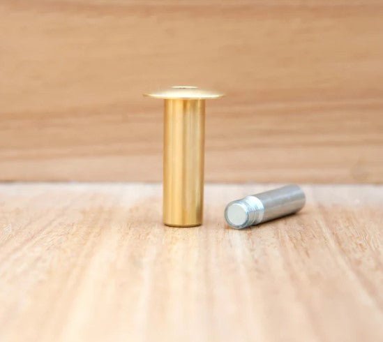 Gold cylindrical object and silver cylindrical object on a wooden surface
