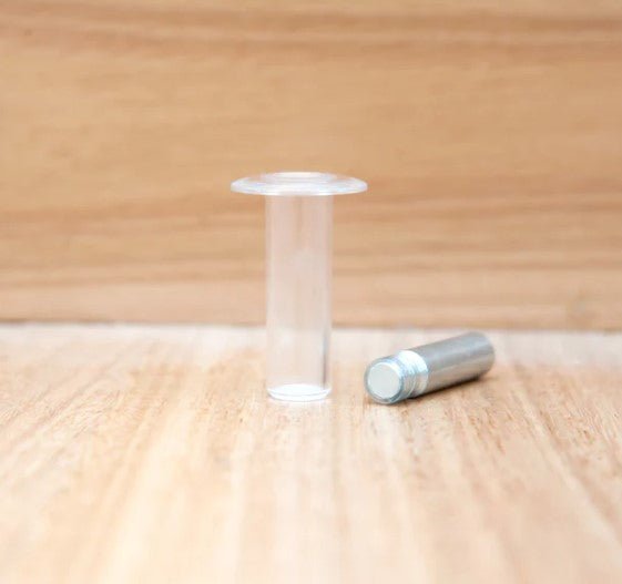 Clear cylindrical object and silver cylindrical object on a wooden surface