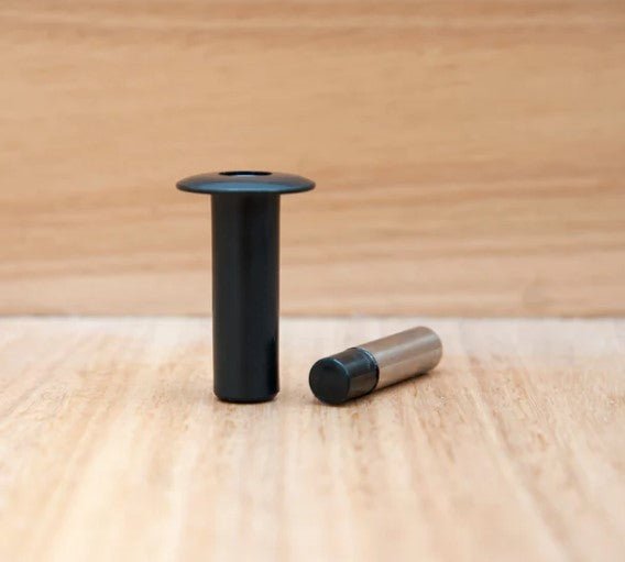 Two black cylindrical objects on a wooden surface