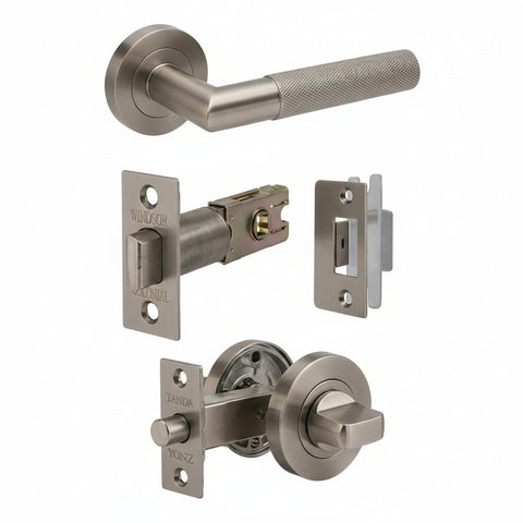 A set of bronze-finished door hardware components on a plain white background, including a lever handle, latch mechanism, lock plate, and deadbolt assembly.