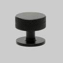 Black textured knob on a white background