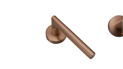 Bronze door handle on a light blue surface with white beads in the background